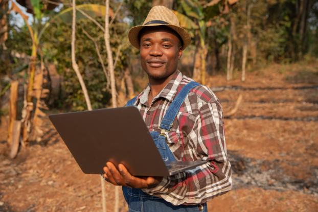 farmer using a computer to access or purchase agricultural insurance, emphasizing the role of technology in making insurance more accessible.